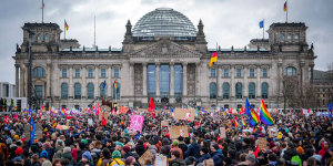 Demonstration von vielen Menschen mit bunten Fahnen vor dem Bundestag.